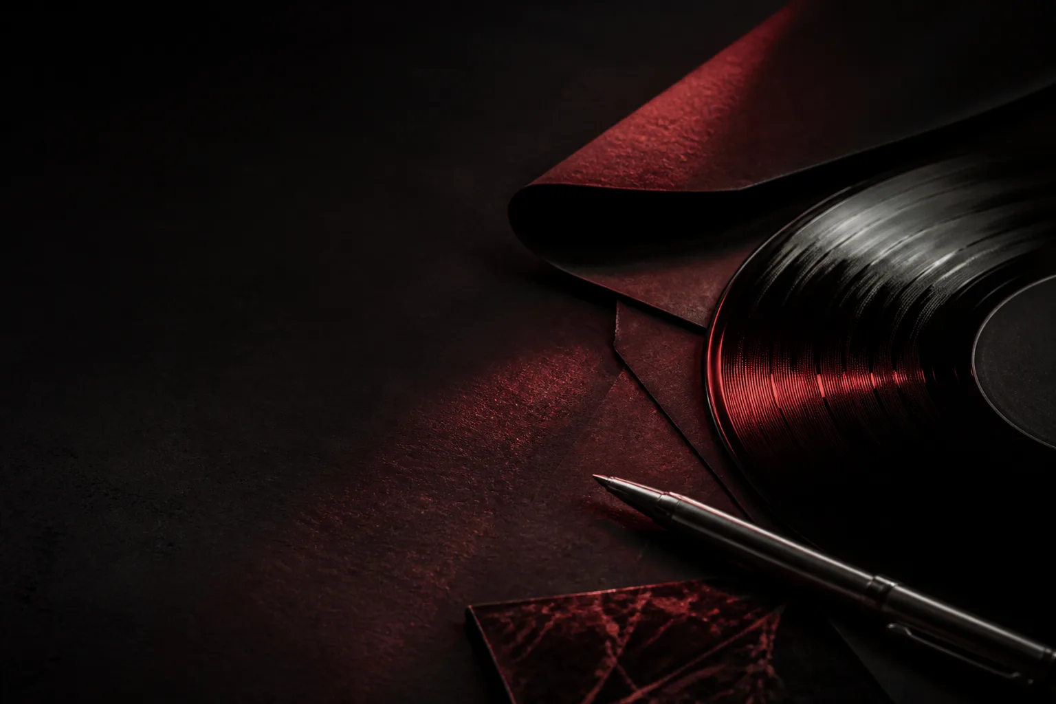 Vinyl record and a pen beside a folded page in red light